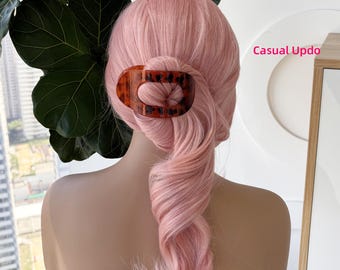 May include: A hair clip with an oval shape and a brown tortoiseshell pattern securing a section of pastel pink hair styled in a casual updo. The text Casual Updo is visible in pink lettering on the right side of the image.