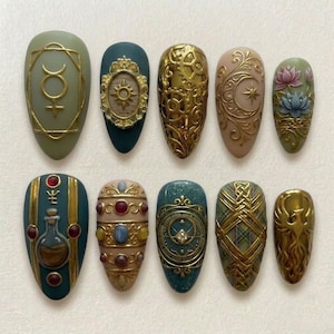 Może przedstawiać: Zestaw dziesięciu sztucznych paznokci w kształcie migdałów z misternymi wzorami. Paznokcie mają różne kolory, w tym oliwkową zieleń, turkus i nude, ze złotymi zdobieniami. Wzory obejmują motywy niebieskie, kwiatowe i bogate detale.