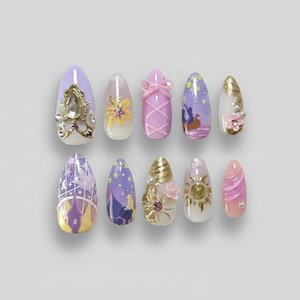 May include: A set of ten artificial nails with various designs. The nails feature a range of colors, including purple, pink, gold, and white. Some nails have intricate embellishments like gems, bows, and floral accents. The designs include floral patterns, and cartoon illustrations.