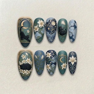 Peut inclure: Dix faux ongles en forme d'amande avec des motifs complexes. Les ongles présentent des illustrations de chats, de lys, de lunes et de ciels étoilés sur une base vert foncé. La palette de couleurs comprend le vert d'eau, le bleu, le blanc et l'or.