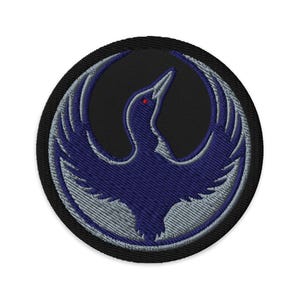 Peut inclure: Écusson brodé avec un motif d'oiseau stylisé en bleu et gris sur fond noir. L'oiseau a un œil rouge et est entouré d'une bordure noire. Idéal pour les vestes, sacs ou autres articles en tissu.