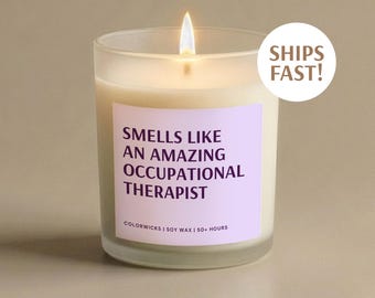 May include: A lit candle in a clear glass jar with a light purple label. The label reads "SMELLS LIKE AN AMAZING OCCUPATIONAL THERAPIST." The candle is on a neutral background. The text "SHIPS FAST!" is on a white circle.
