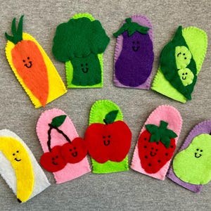 May include: Set of 10 felt finger puppets shaped like different fruits and vegetables. The puppets have smiling faces and are in various colors, including green, purple, red, orange, and yellow.
