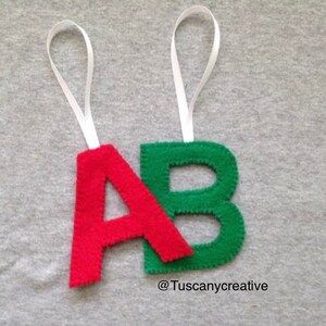 May include: Two felt letter ornaments, one red "A" and one green "B", with white ribbon loops for hanging.