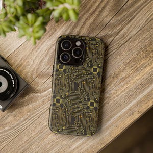 May include: Black phone case with a gold circuit board design. The case has a glossy finish and features a detailed pattern of electronic pathways and components. The phone case is on a wooden surface.