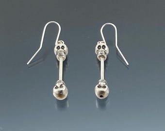 May include: A pair of silver skull dangle earrings. Each earring features two silver skull beads.