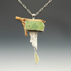 mixed metal necklace of sterling silver roller printed in a floral pattern and a natural twig cast in bronze green prehnite stone and glass