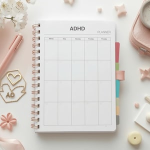Könnte beinhalten: Ein offener, spiralgebundener ADHD-Planer mit leerem Wochenlayout, umgeben von rosa Accessoires, darunter ein Stift, eine kleine Tasche und dekorative Formen. Der Planer ist mit "ADHD PLANNER" beschriftet.