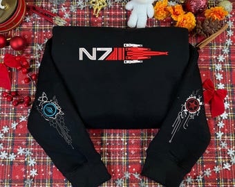 May include: Black sweatshirt with the text "NZ" in white and a red and white graphic. The sleeves feature white and red graphics. The sweatshirt is displayed on a red and white plaid surface with Christmas decorations.