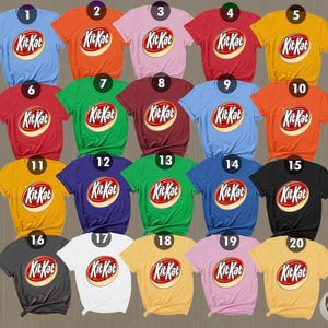 Pode incluir: Uma coleção de vinte camisetas de manga curta em várias cores sólidas, cada uma com o logotipo KitKat impresso no centro. As camisetas estão dispostas em uma grade, exibindo cores que incluem azul, laranja, rosa, vermelho, amarelo, verde e preto.