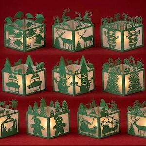 Peut inclure: Un ensemble de onze photophores carrés en papier vert avec des motifs de Noël découpés, représentant le Père Noël, des rennes, des bonhommes de neige, des sapins, des bonshommes en pain d'épices et des crèches, éclairés par une lumière chaude.