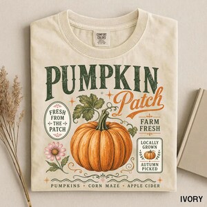 Peut inclure: Un t-shirt à col rond couleur ivoire avec une impression graphique portant le texte PUMPKIN Patch. Le motif comprend une grosse citrouille orange, une fleur rose et un petit texte indiquant Fresh From The Patch, Farm Fresh et Locally Grown Autumn Picked.