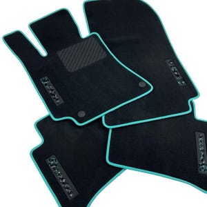 Puede incluir: Alfombrillas negras para coche con ribete turquesa. Las alfombrillas tienen una superficie texturizada y un emblema decorativo. El juego incluye alfombrillas para el conductor y el pasajero, así como la parte trasera.