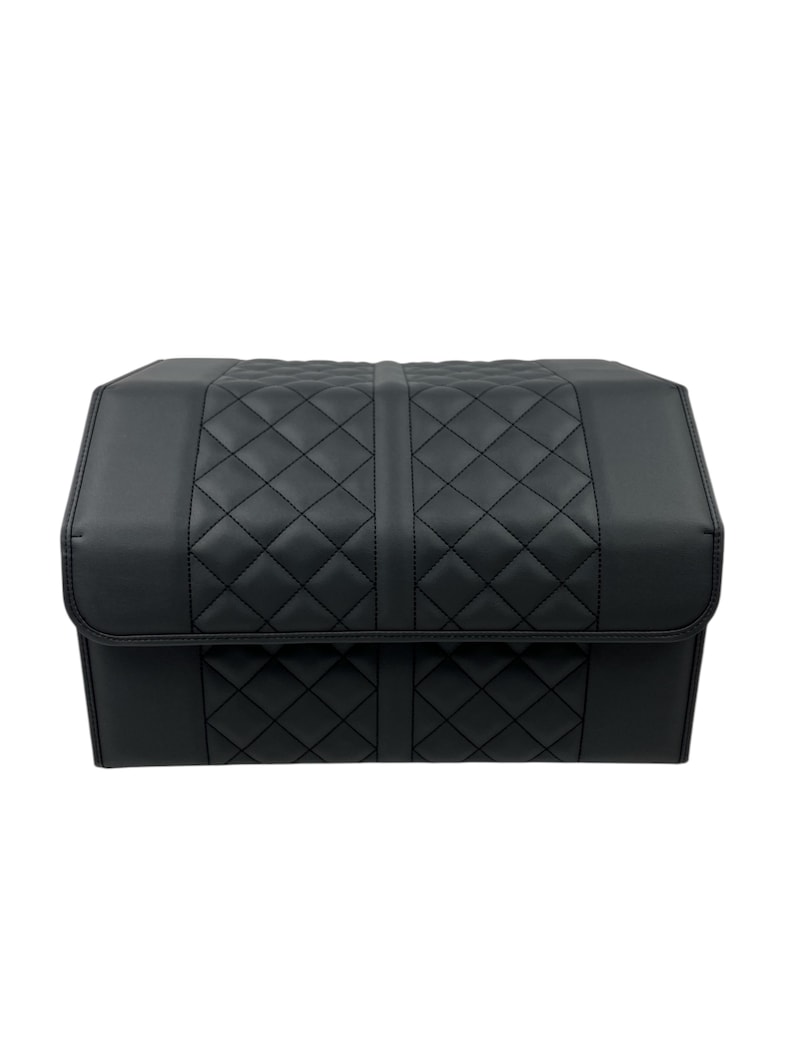 May include: Black, quilted storage container with a rectangular shape. The container features a diamond pattern on the top and front panels, with a solid black finish. The lid folds over the front, and the container is designed for storage.