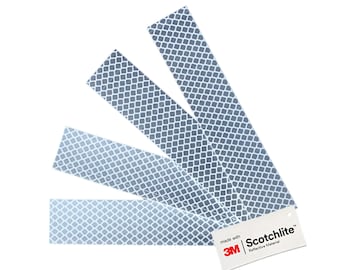 Könnte beinhalten: Vier reflektierende Streifen in Grau und Weiß mit einem Gittermuster. Die Streifen sind schräg angeordnet. Ein kleines weißes Etikett mit dem Text "Scotchlite Reflective Material" befindet sich unten rechts.