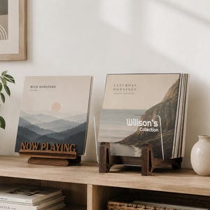 Op de afbeelding: Twee donkerhouten vinylplatenhouders met albumhoezen. De linkerhouder heeft de tekst NOW PLAYING en bevat een plaat genaamd WILD HORIZONS. De rechterhouder bevat een stapel platen met de tekst Willson's Collection op de hoes.