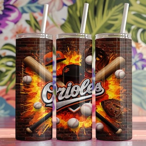 Könnte beinhalten: Ein Edelstahlbecher mit Baseball-Motiv. Der Becher hat einen Ziegelhintergrund mit orangefarbenen und gelben Flammen, Baseballschlägern, Baseballs und dem Wort "Orioles".