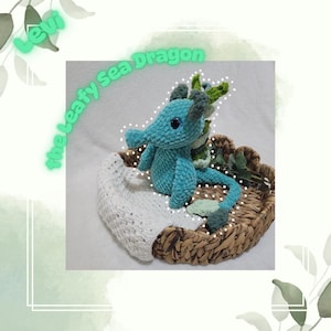 May include: A crocheted sea dragon plush toy in teal blue with green leafy accents. The toy is sitting in a woven basket with a white crocheted blanket.