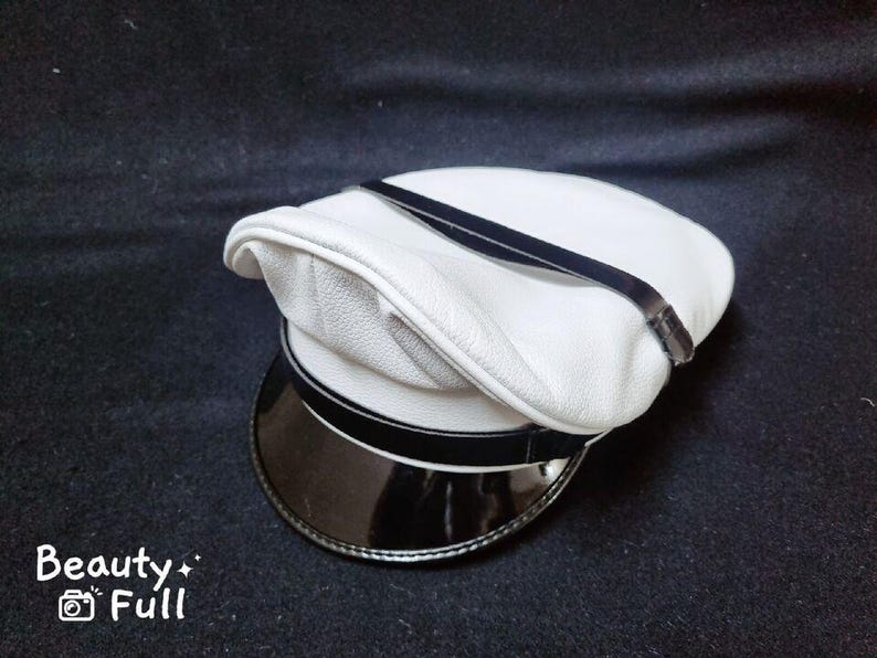 Puede incluir: Un sombrero de cuero blanco con una banda negra y un ala de charol negro.