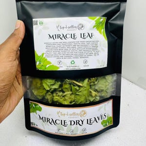 May include: A black bag of Miracle Leaf dry leaves. The bag has a clear window showing the green leaves inside. The bag has white labels with the words "Miracle Leaf" and "Miracle Dry Leaves". The bag also has text about the product's benefits.