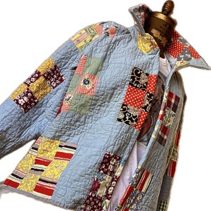 May include: A blue quilted jacket with a patchwork design featuring various colors and patterns, including red, yellow, green, and floral prints.