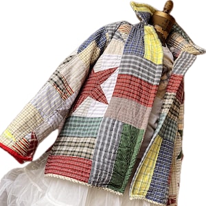 May include: A patchwork jacket with a red star design. The jacket features a variety of fabric patterns, including plaid and stripes, in shades of red, blue, green, and yellow. The jacket is quilted and has a collar.