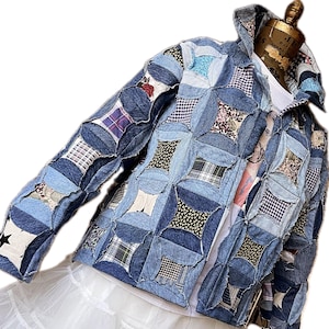 May include: A blue denim jacket made from patchwork fabric. The jacket is quilted with different shades of blue denim and features a variety of patterns, including plaid, floral, and geometric designs.