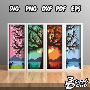 May include: Four framed paper cut art pieces depicting trees in different seasons: spring blossoms, summer green, autumn leaves, and winter ice. Each scene includes a lake and mountains, with the words "SVG PNG DXF PDF EPS" at the top.