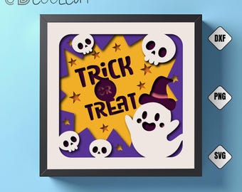 May include: A framed Halloween-themed paper art piece. The design features a ghost, skulls, stars, and the words "Trick or Treat" in a layered, cutout style. The color palette includes white, purple, orange, and black.