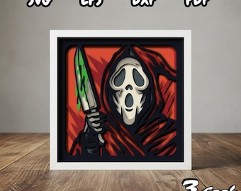 May include: A framed, layered paper art piece featuring the Ghostface character from the Scream horror film series. The artwork depicts Ghostface holding a knife with green blood. The frame is white, and the background is red.