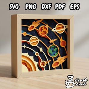 May include: A layered paper art piece depicting a colorful solar system scene with planets, stars, and rockets, set within a light wood frame. The artwork includes the text "SVG PNG DXF PDF EPS" and the logo "3 Cool Cut".