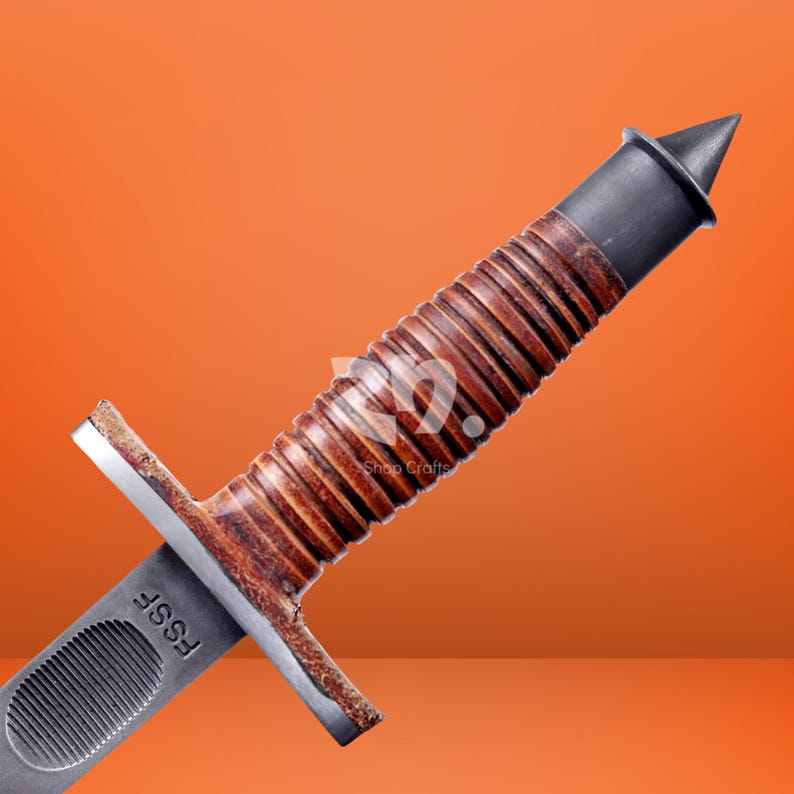 May include: A combat knife featuring a brown, ribbed leather-wrapped handle, a dark metal pommel with a pointed tip, and a silver-toned metal crossguard. The blade base is marked with the letters FSSF and features a textured oval grip section.