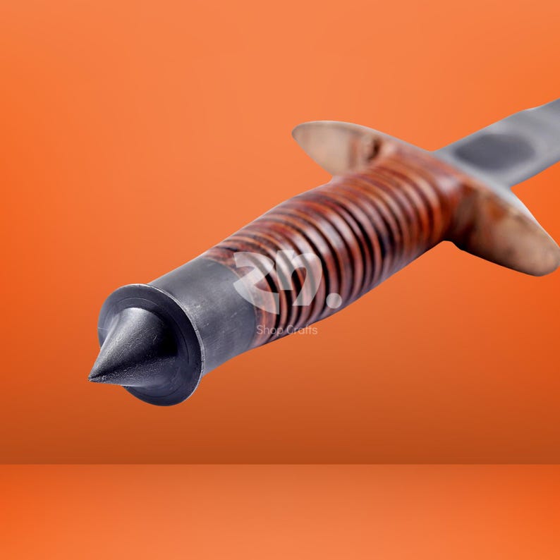 May include: A knife handle featuring a brown, ribbed, cylindrical grip made of stacked leather rings, a dark metal pommel with a pointed tip, and a metal crossguard. The handle is positioned diagonally against a solid orange background.
