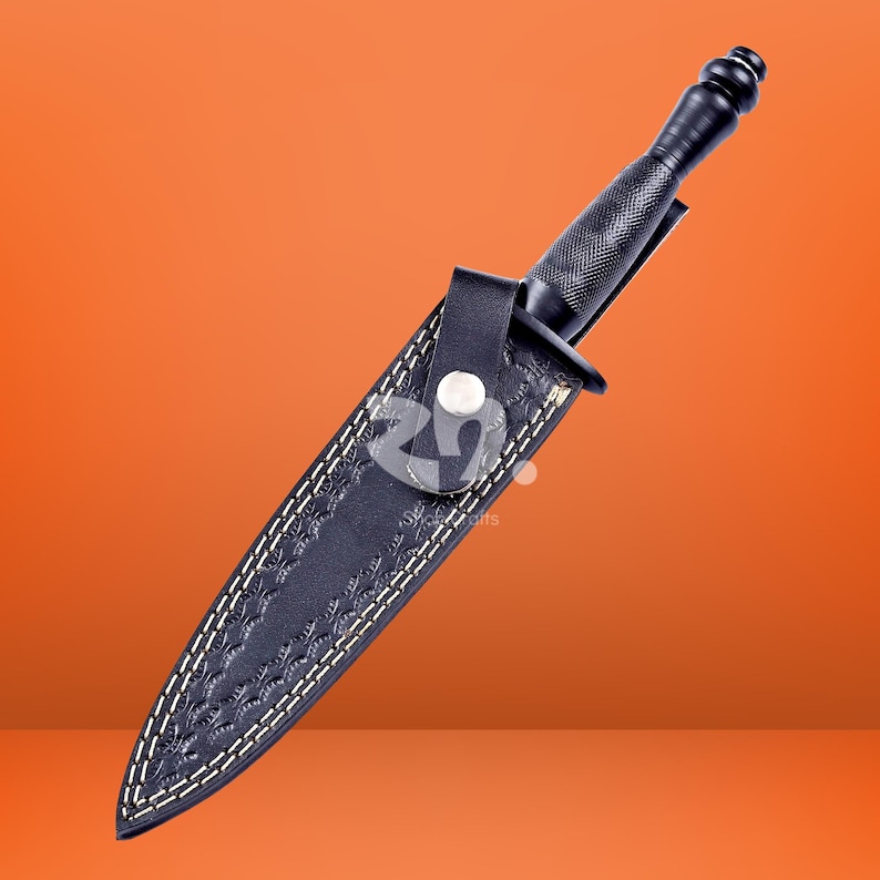 May include: A black dagger with a textured handle and a matching black leather sheath. The sheath features a decorative embossed pattern, white contrast stitching, and a single snap button closure to secure the blade in place.