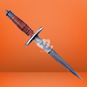 May include: A double-edged stiletto knife featuring a brown leather-wrapped handle with a series of horizontal ridges, a metal pommel, a crossguard, and a steel blade stamped with the text V-42 USA near the hilt, presented against an orange background.