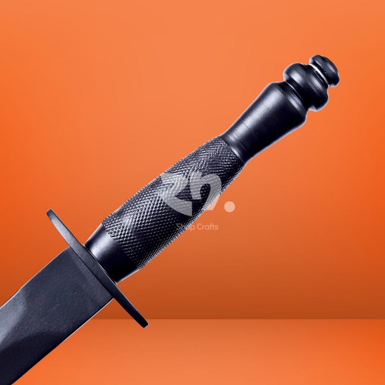 May include: A black dagger featuring a textured, diamond-patterned grip and a smooth, rounded pommel. The handle is separated from the blade by a straight, flat crossguard. A faint logo and the text Shop Crafts are visible on the handle.