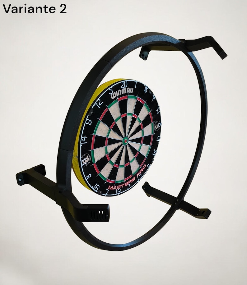 K&ouml;nnte beinhalten: Ein schwarzer Dartscheibenst&auml;nder aus Metall mit einer Winmau Dartscheibe. Die Dartscheibe hat einen gelben Au&szlig;enring, schwarze und gr&uuml;ne Bereiche und wei&szlig;e Zahlen. Der St&auml;nder hat ein gebogenes Design und ist an einer Wand montiert.