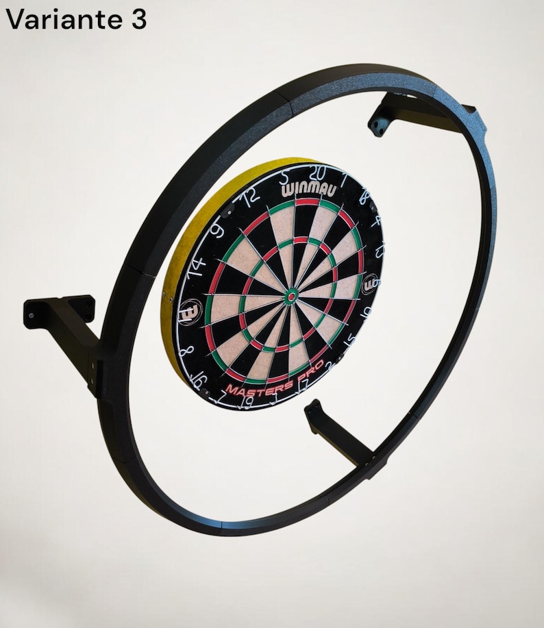 K&ouml;nnte beinhalten: Ein schwarzer Dartscheibenrahmen aus Metall mit einer Winmau Dartscheibe. Die Dartscheibe hat ein Farbschema in Schwarz, Rot, Gelb und Wei&szlig;. Der Text "Variante 3" befindet sich oben links. Die Dartscheibe ist an einer Wand befestigt.