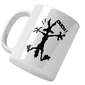 May include: White ceramic coffee mug featuring a black silhouette of a cartoon character with the text "OUCH!" printed on the side.