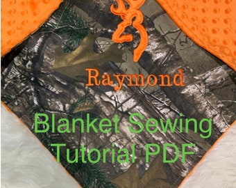 May include: A baby blanket with a camouflage pattern and orange minky fabric. The blanket features the name "Raymond" embroidered in orange, along with a brown logo. The text "Blanket Sewing Tutorial PDF" is also visible.