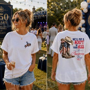 May include: A white t-shirt featuring a small graphic of a cowboy on a bucking horse on the front left chest. The back displays a large graphic of a cowboy hat and a western boot with an American flag pattern, with the text We'll put a boot in your ass the American Way.