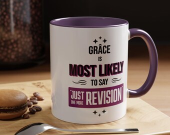 May include: White ceramic mug with a purple rim and handle. The mug has a quote in purple text that reads "Grace is most likely to say "Just one more revision" "