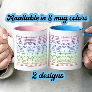 Op de afbeelding: Twee witte keramische mokken met kleurrijke regenboogontwerpen. Eén mok heeft een roze binnenkant en handvat, de andere heeft een blauwe binnenkant en handvat. De tekst op de afbeelding luidt "Verkrijgbaar in 8 mokkleuren" en "2 ontwerpen".