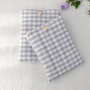 May include: Two rectangular fabric pouches featuring a light purple and white gingham check pattern. Each pouch is secured at the top center with a small, round, light-colored wooden button and a matching fabric loop closure.
