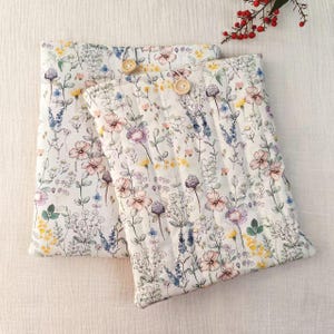 Peut inclure: Deux taies d'oreiller blanches à motifs floraux avec un design botanique de fleurs roses, violettes et jaunes. Chaque taie d'oreiller a une fermeture à bouton en bois. Les taies d'oreiller sont matelassées avec des coutures verticales.
