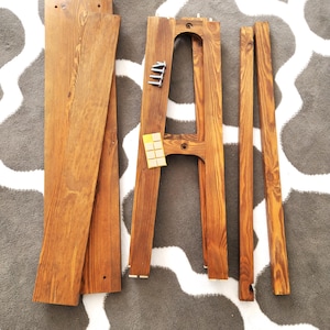 Puede incluir: Un conjunto de piezas de muebles de madera para ensamblar una unidad de estanter&iacute;a. Las piezas est&aacute;n te&ntilde;idas de un color marr&oacute;n oscuro e incluyen dos tablas largas, dos tablas m&aacute;s cortas y dos soportes verticales. Tambi&eacute;n se incluyen peque&ntilde;os tornillos de metal.