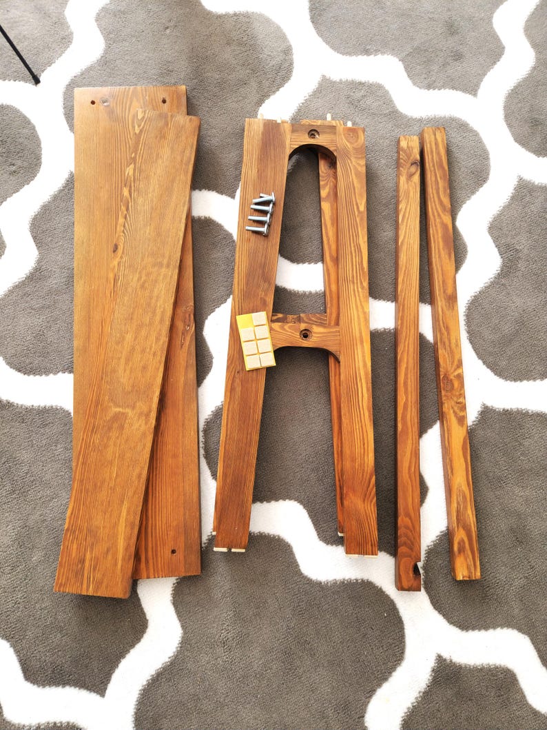 Puede incluir: Un conjunto de piezas de muebles de madera para ensamblar una unidad de estanter&iacute;a. Las piezas est&aacute;n te&ntilde;idas de un color marr&oacute;n oscuro e incluyen dos tablas largas, dos tablas m&aacute;s cortas y dos soportes verticales. Tambi&eacute;n se incluyen peque&ntilde;os tornillos de metal.