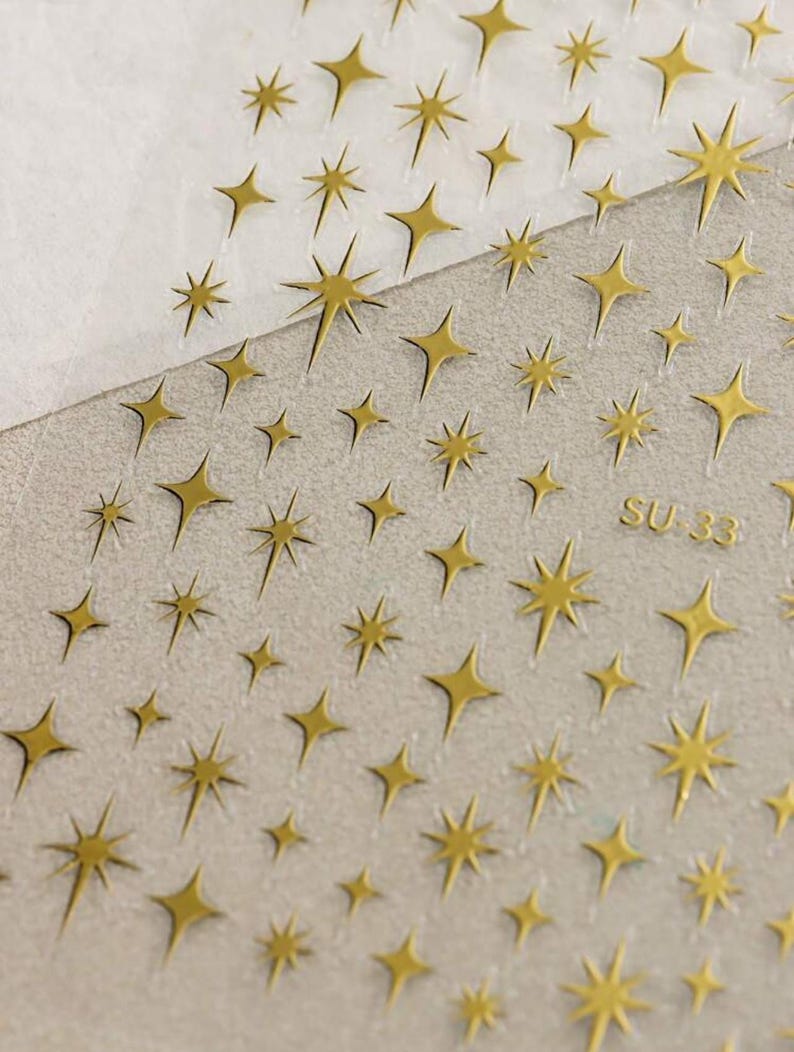 May include: A sheet of clear adhesive paper with gold glitter stars printed on it. The sheet is labeled "SU 33".