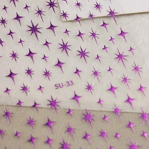 May include: A sheet of clear adhesive paper with a repeating pattern of purple glitter stars. The sheet is labeled "SU-33".