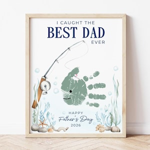 May include: Framed print with the text "I Caught the Best Dad Ever" in navy blue. A fishing rod and a handprint fish design are featured. The words "Happy Father's Day 2026" are also included. The print has a light wood frame.